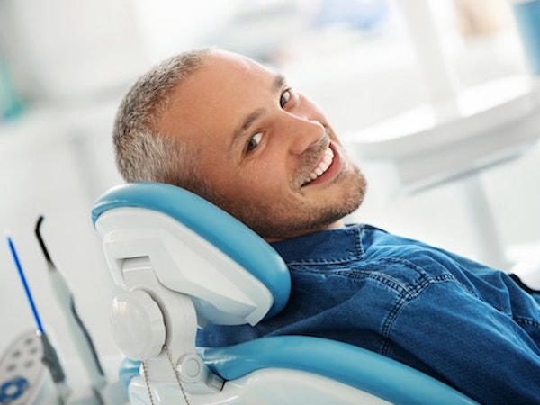 Man in a denim shirt laying down discussing our services with our dentist